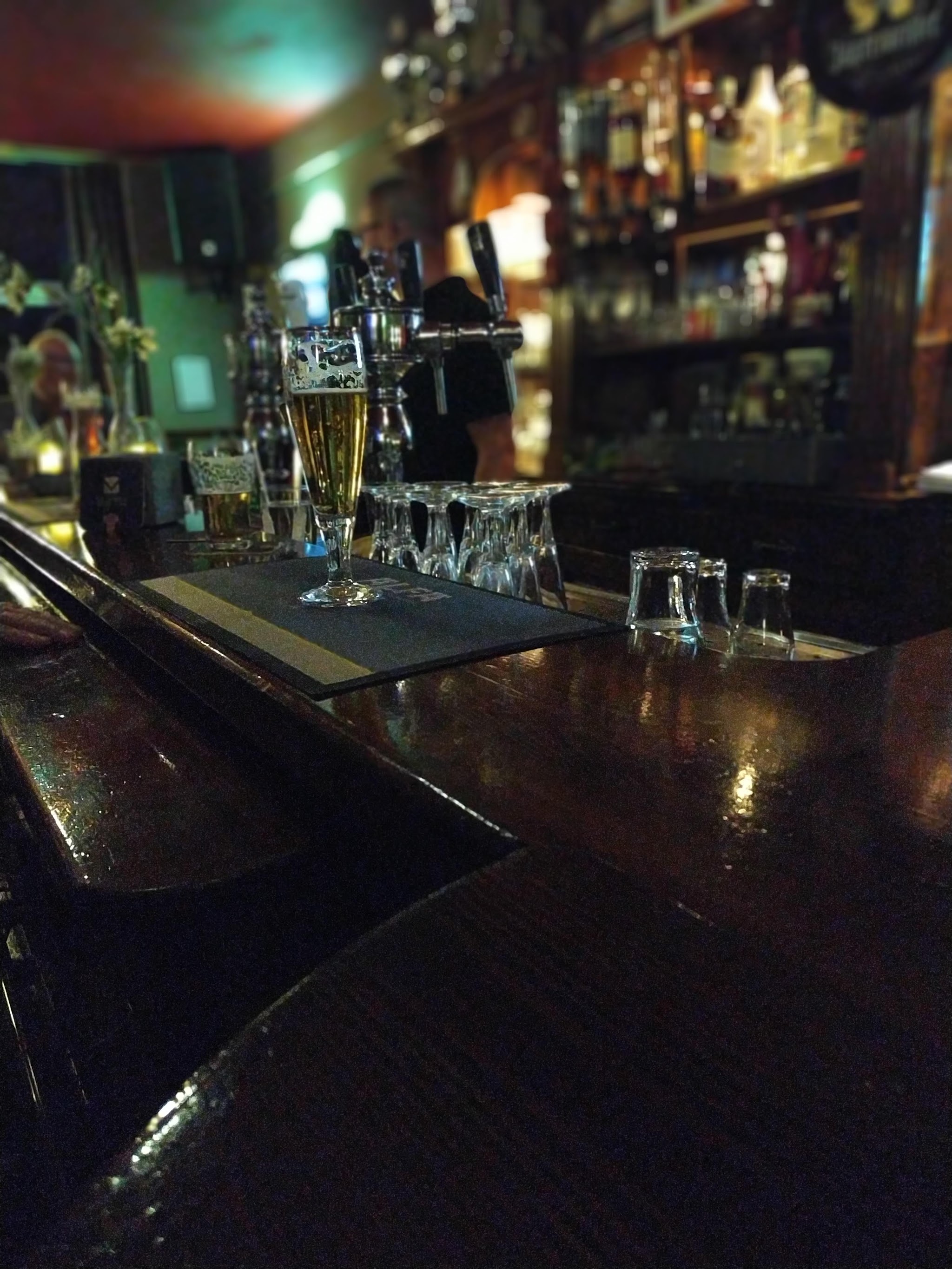 De bar met een glas bier, de taps en de flessenwand erachter